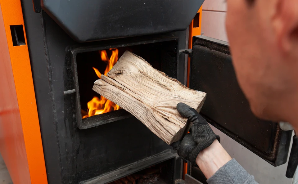 Installateur professionnel en salopette et gants bleus installant un conduit de ventilation noir dans un comble aménagé