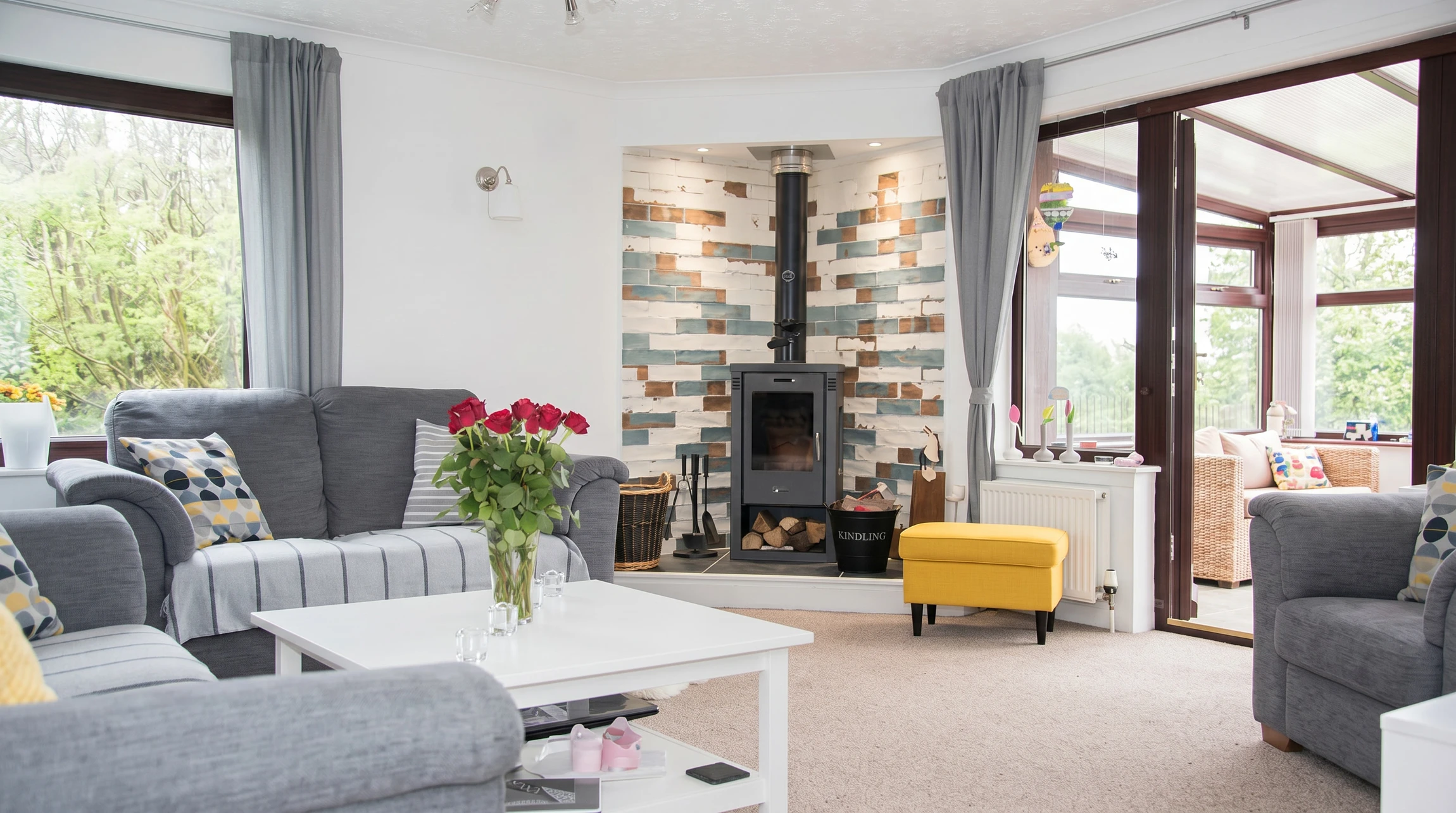 Intérieur chaleureux avec cheminée en pierre naturelle en fonctionnement, flammes vives visibles derrière vitre de protection