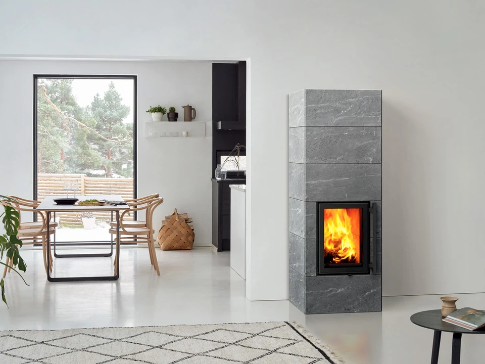 Intérieur nordique élégant avec poêle de masse en stéatite grise, vitre de combustion rectangulaire révélant des flammes vives