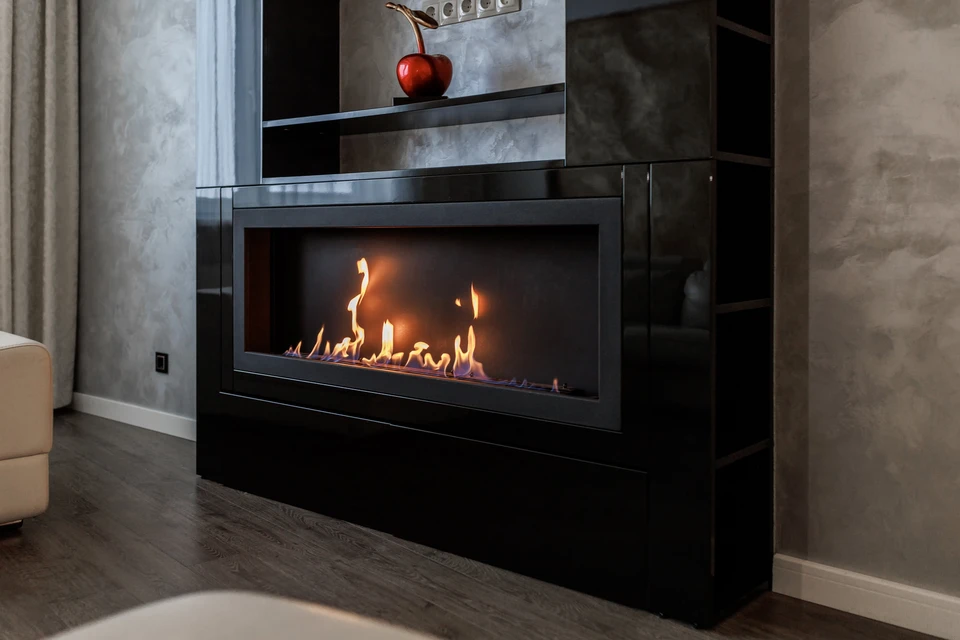 Salon de luxe avec cheminée à gaz en fonctionnement, canapés gris et fauteuils beiges disposés autour d'une table basse